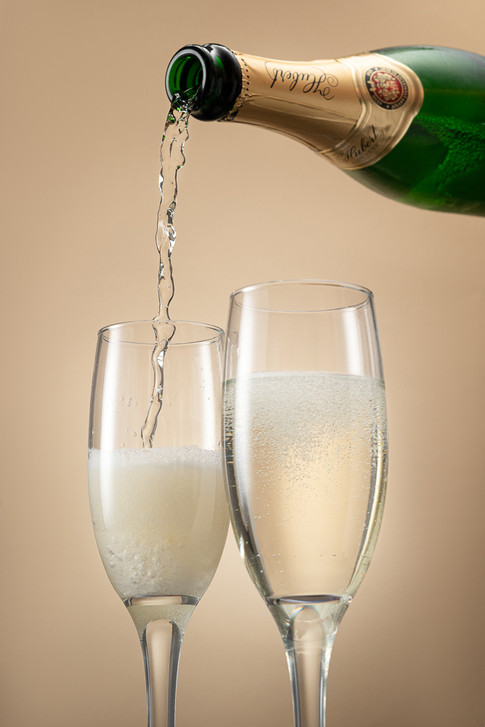 Huber sa leje z vysky do pohara na sampanske na kremovom pozadi. 