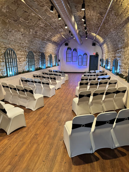 Elegant stone-walled Banquet Venue in Columbus Ohio set with white chairs and black sashes.