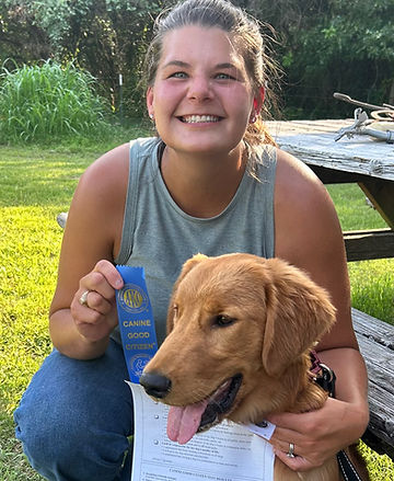 Kristin and Buddy proudly displaying Buddy's hard earned AKC Canine Good Citizen ribbon after passing assessment.