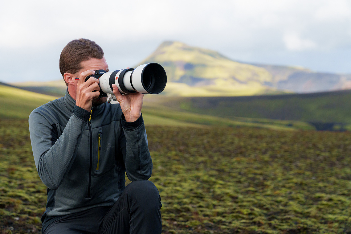 Photographer with a telephoto lens in a mountain landscape