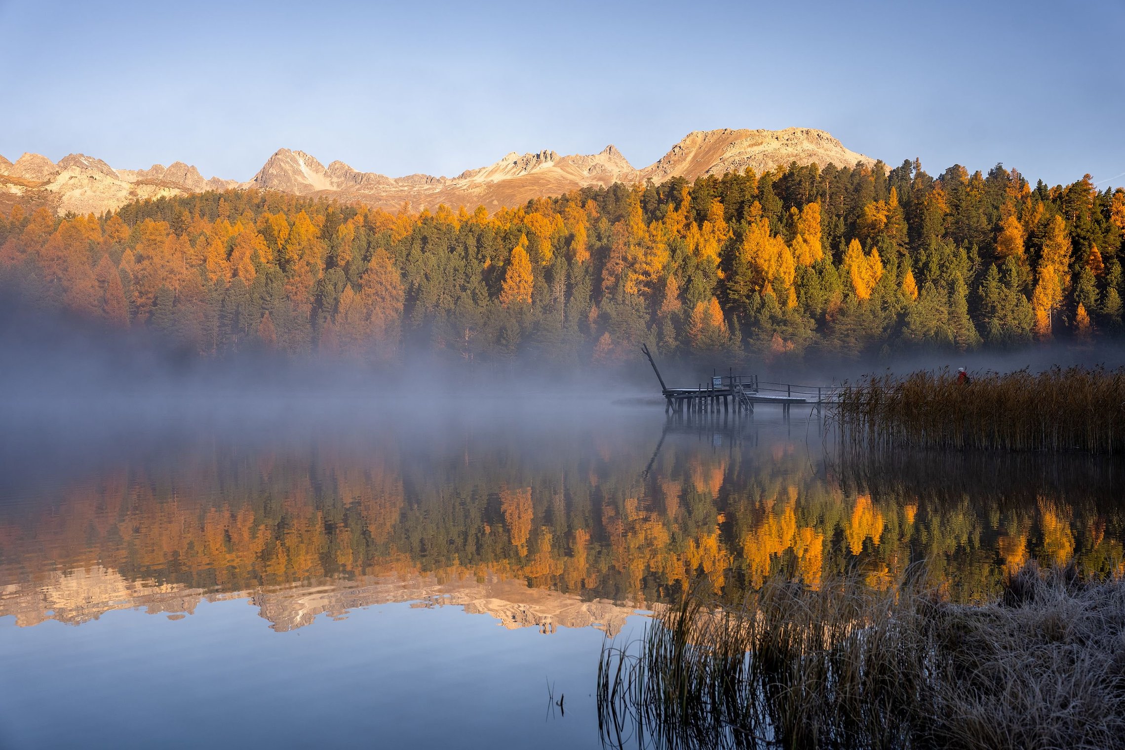 Stazersee im ersten Licht mit stillem Wasser und einsamem Steg