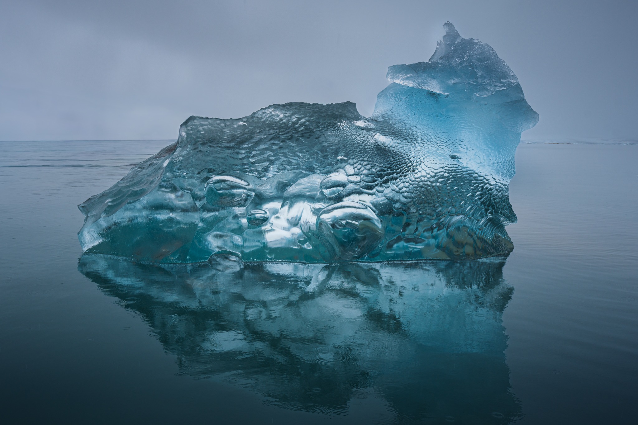 Transparent block of ice with trapped air bubbles and cracks in calm water
