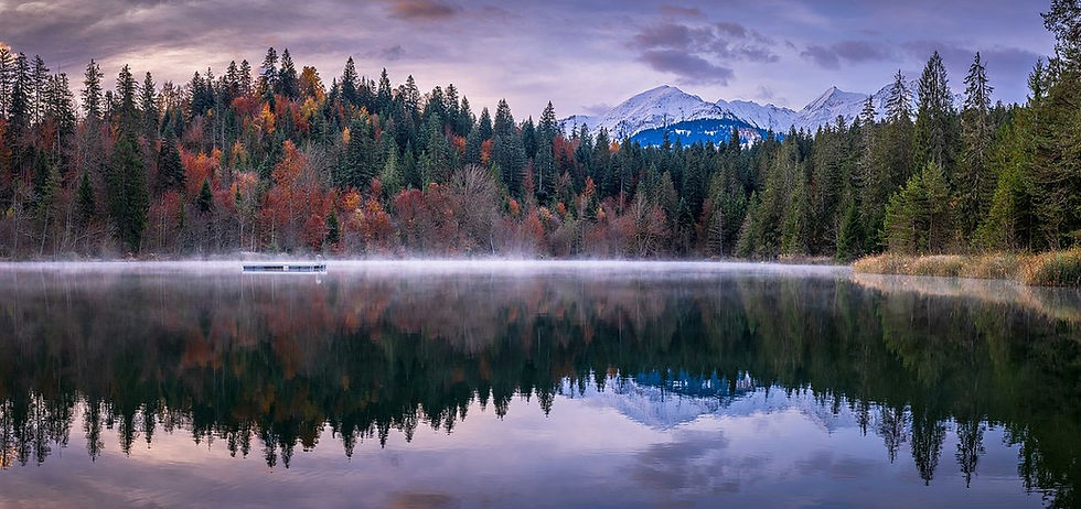 Herbstfarben und schneebedeckte Gipfel spiegeln sich im stillen Crestasee