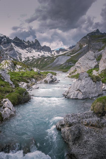 Bergbach zwischen grauen Kalkfelsen unter schweren Wolken in Flims