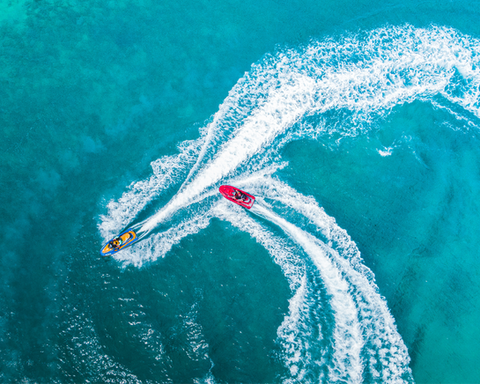 Vue aérienne de jetskis en action sur une mer turquoise, illustrant une activité nautique dynamique et excitante proposée en Guadeloupe.