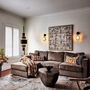 Rich layered textures featuring a high and low pile rug, a boucle ottoman, intricate artwork, plush throws and pillows, and rich botanical accents adding depth and dimension to the space. 