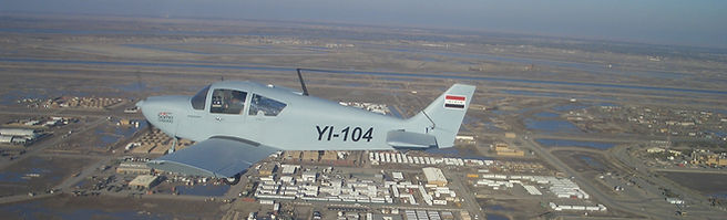 A small airplane in flight, marked with 'YI-104', above landscape overview.