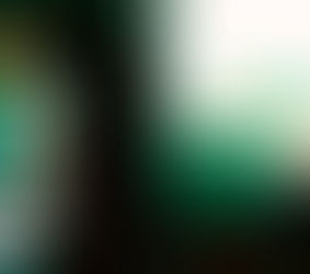 Homem de casaco azul sentado dentro de um comboio, com a cabeça baixa e uma mochila ao lado, representando a frustração e a espera.