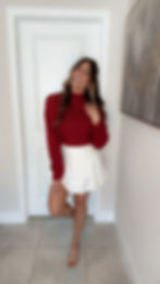 Woman in red sweater and white skirt.
