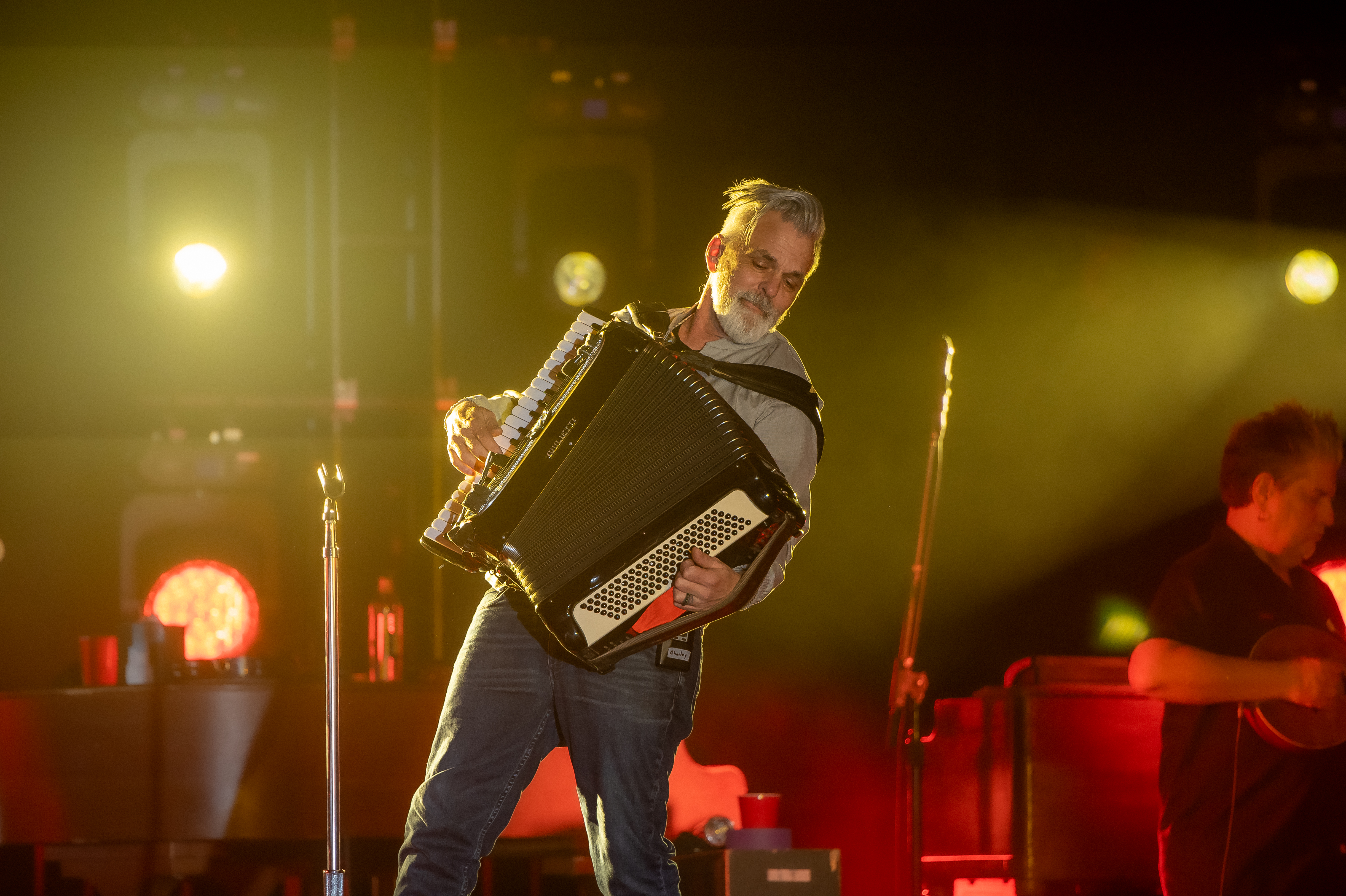 Band member playing accordion passionately at Coca-Cola 2024 Final Four concert.

