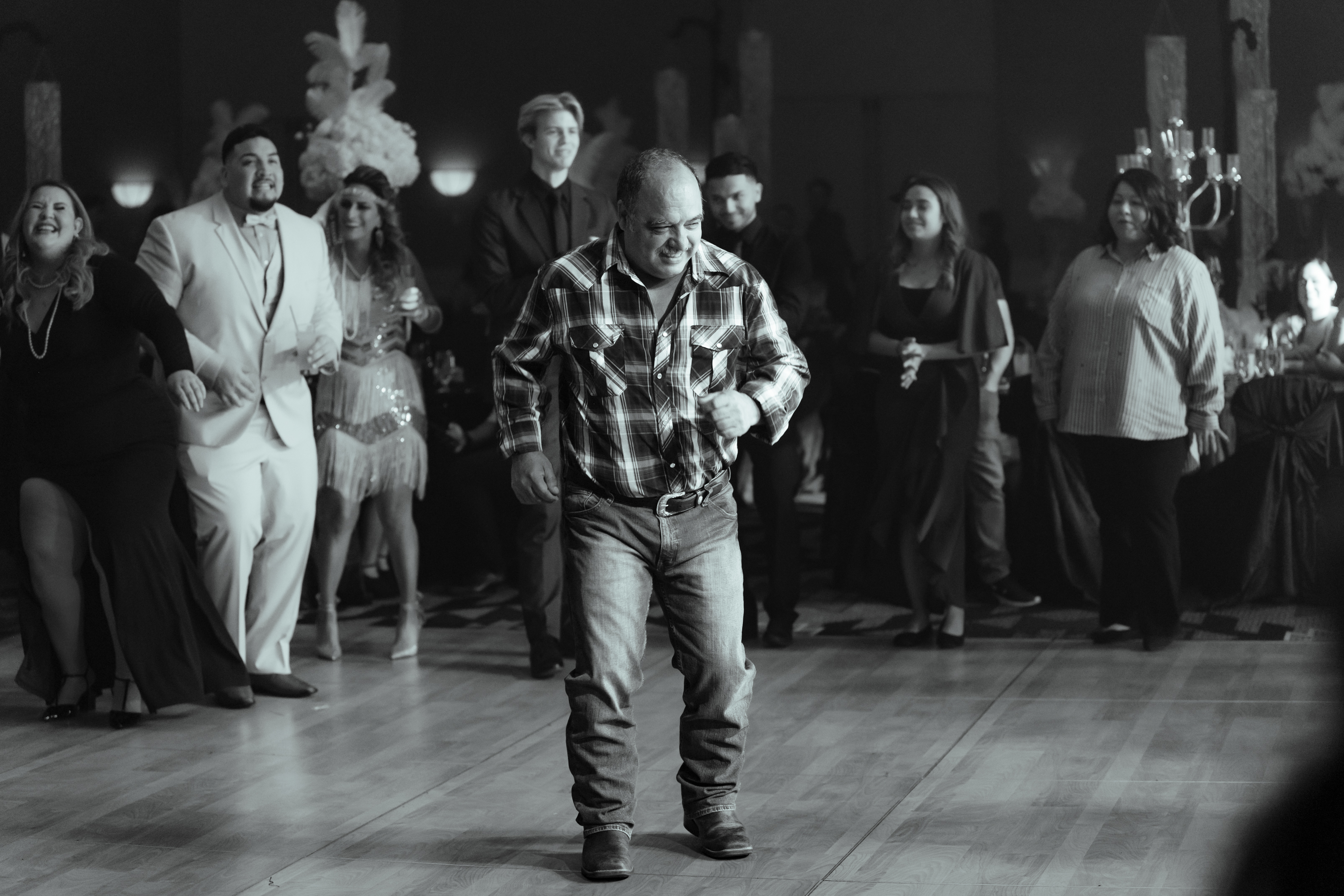 Man dancing at Gatsby-themed company banquet with guests cheering.
