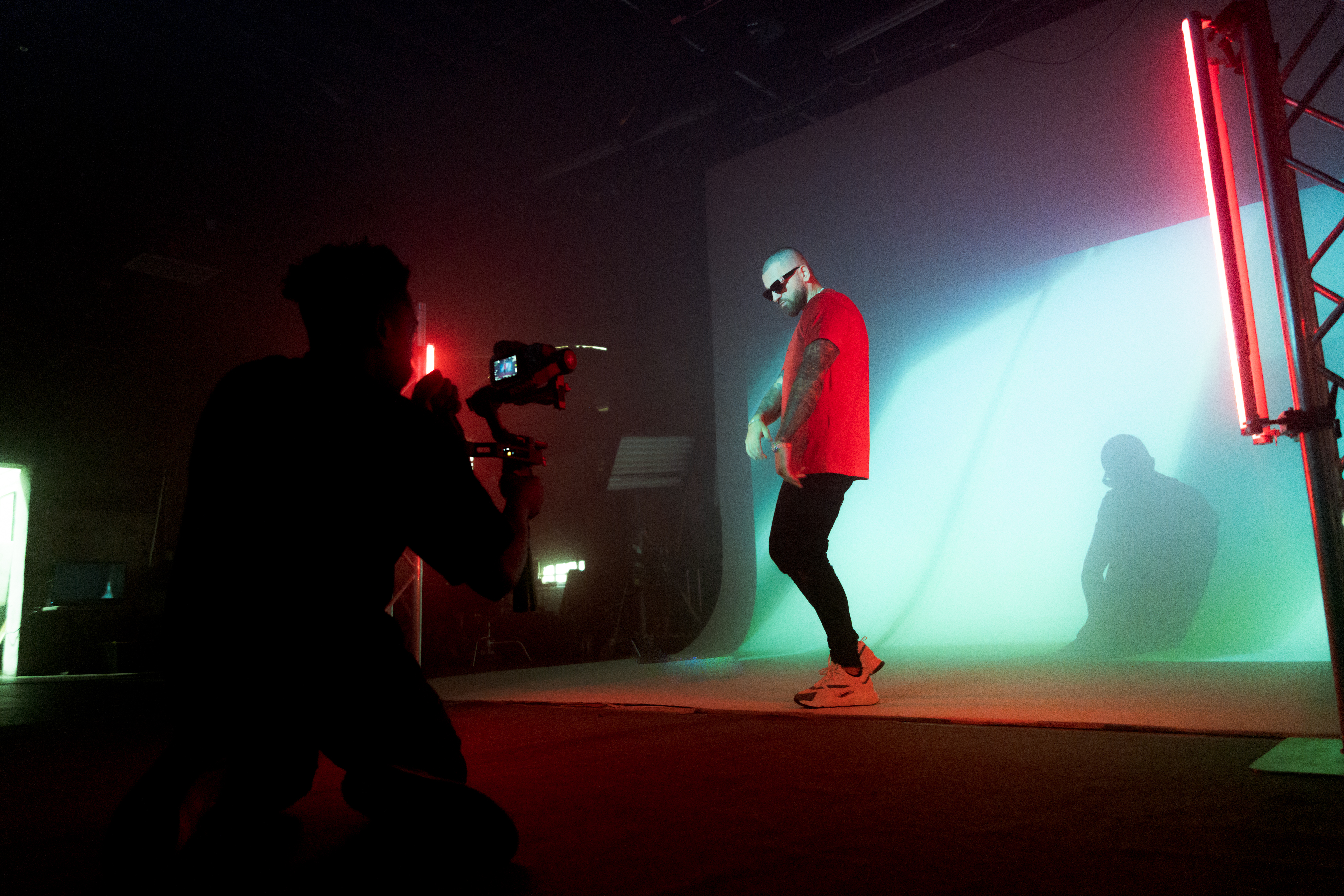 Wide behind-the-scenes shot of Bandman music video with Drei singing, studio and cyc wall visible, highlighting the production level of the studio.

