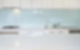 white kitchen with white stone wurfaces worktops and a white glass splashback