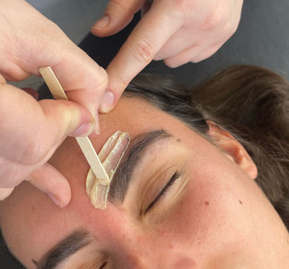 Woman applying wax around eyebrows.