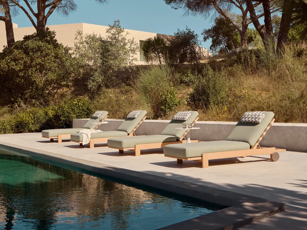 Kubik sun loungers beside a pool, showing weatherproof outdoor furniture with warm TechTeak frames.