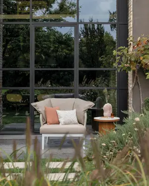 DREAM outdoor armchair featuring a curved rope‑woven backrest, durable aluminium structure, and weather‑resistant cushions.