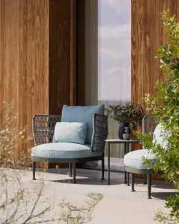 CURIO Armchairs positioned on a stylish outdoor patio with lush greenery.