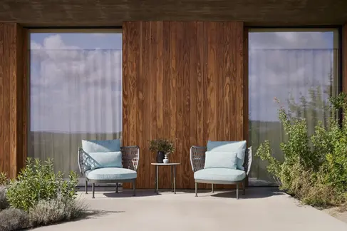 CURIO Armchairs positioned on a stylish outdoor patio with lush greenery.