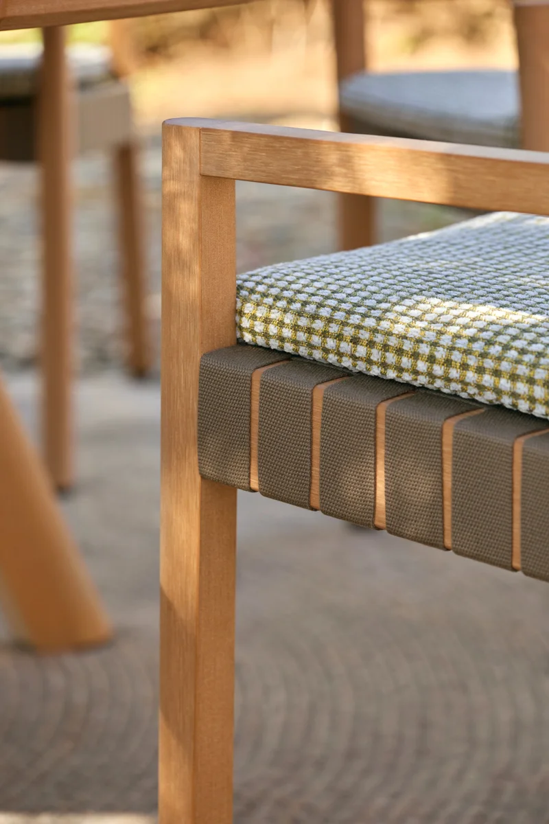 Close-up of Kubik outdoor chair with woven seat detail, patterned cushion and warm TechTeak frame.