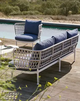 CURIO Armchair and Sofa positioned on a stylish outdoor deck with lush greenery.