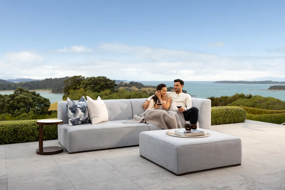 Couple relaxing on Azur outdoor sofa with sea views, ideal for luxurious outdoor living NZ.