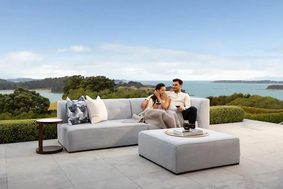 Couple relaxing on Azur outdoor sofa with sea views, ideal for luxurious outdoor living NZ.