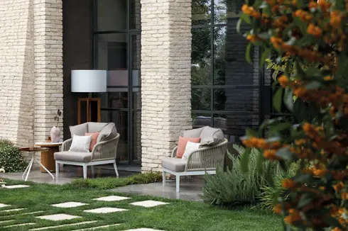 DREAM outdoor armchair featuring a curved rope‑woven backrest, durable aluminium structure, and weather‑resistant cushions.