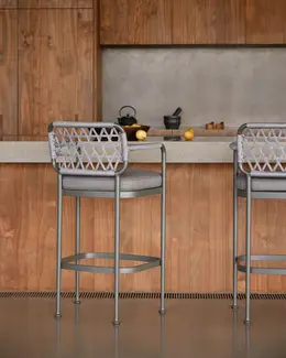 Pair of CURIO Bar Stools on a patio, highlighting sleek design and braided backrest.
