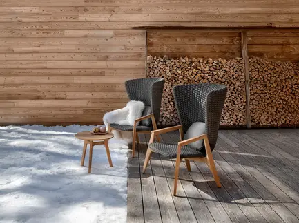 KNIT high-back outdoor lounge armchair in teak and woven rope in an outdoor setting