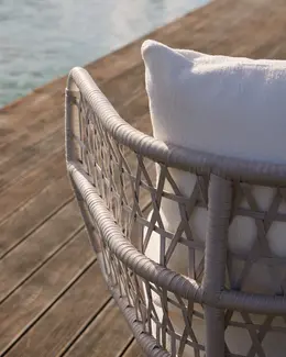 CURIO Armchair positioned on a stylish outdoor deck with lush greenery.