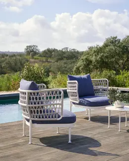 CURIO Armchair positioned on a stylish outdoor deck with lush greenery.