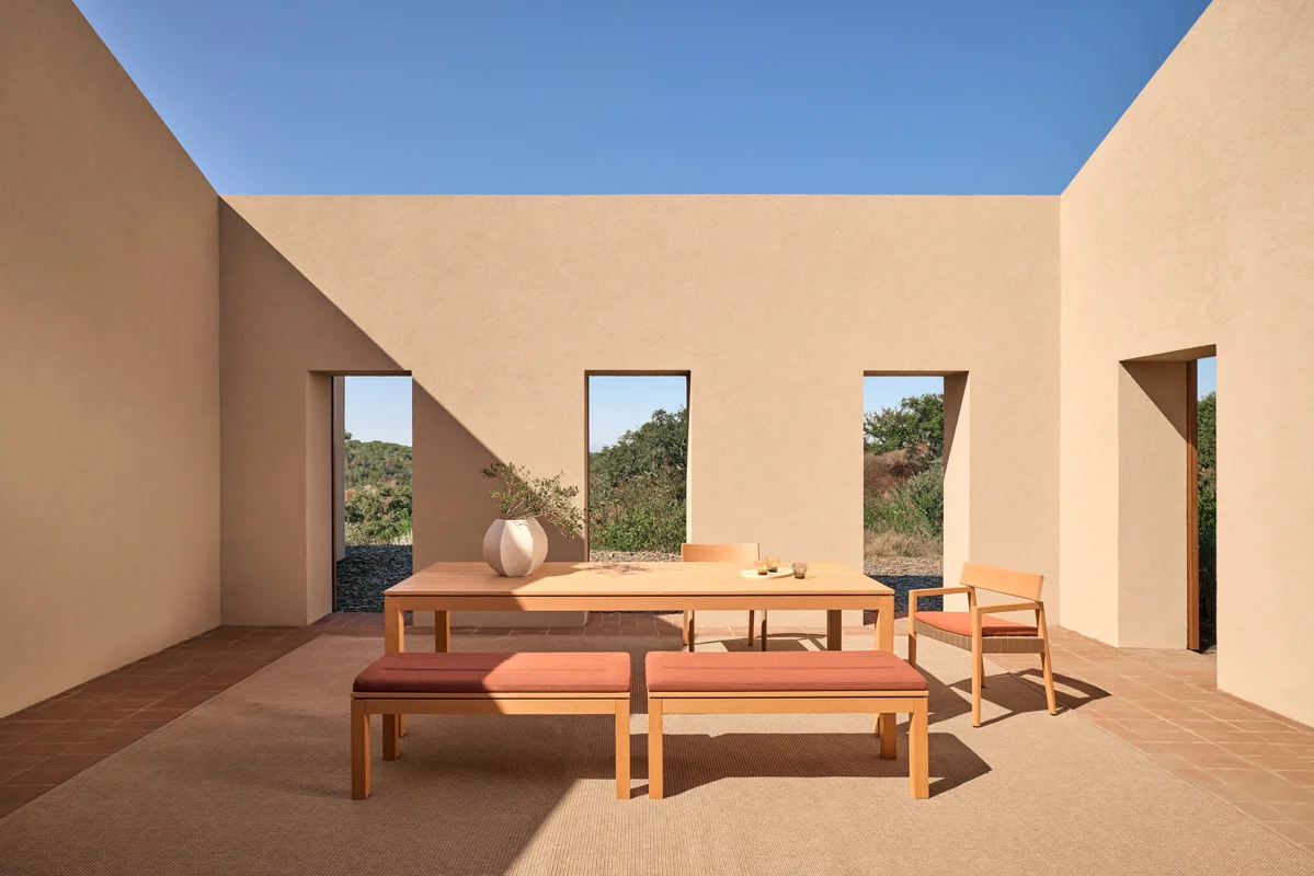 Kubik outdoor dining table with bench seating in a sheltered courtyard with clean architectural lines.