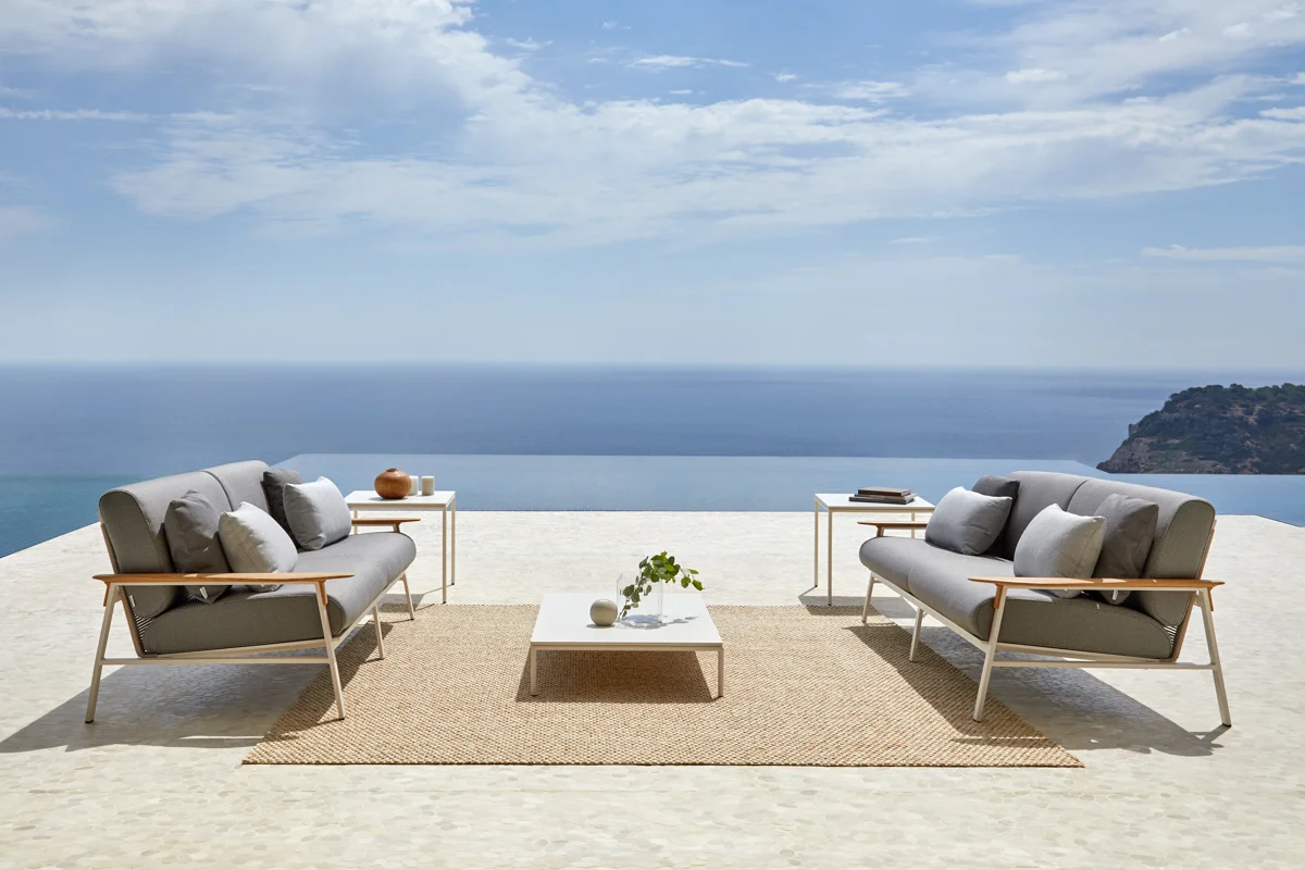 Outdoor rug anchoring a seaside outdoor lounge furniture seating area, adding warmth and defining the space.