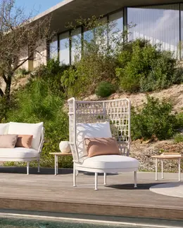 CURIO Highback Armchair positioned on a stylish outdoor deck with lush greenery.