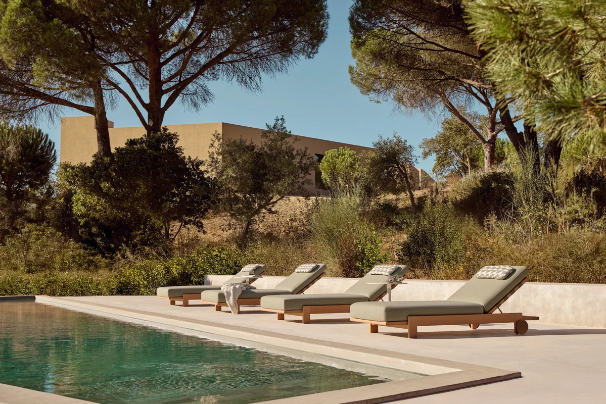 POINT Rivoli outdoor loungers with pale green cushions arranged beside a pool, surrounded by mature trees and natural planting.