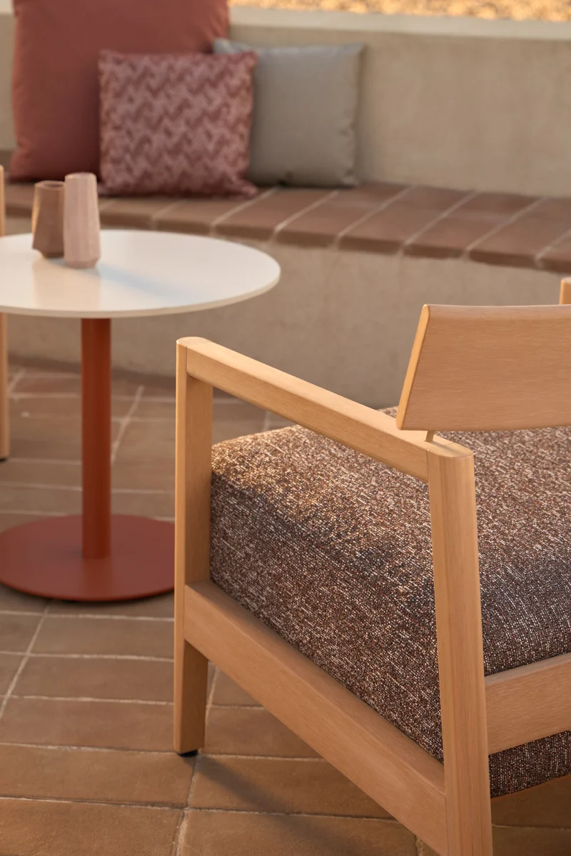 Close-up of Kubik lounge chair armrest and cushion detail, showing warm TechTeak texture and refined outdoor styling.