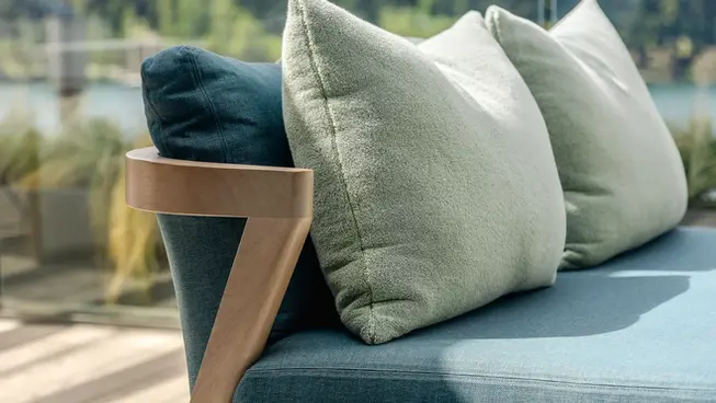 Coco Wolf bench seating with layered green cushions on the ROKI terrace, backdropped by alpine trees and mountains.