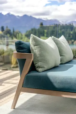Coco Wolf bench seating with layered green cushions on the ROKI terrace, backdropped by alpine trees and mountains.