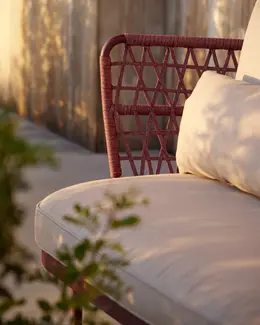 CURIO Armchair positioned on a stylish outdoor deck with lush greenery.