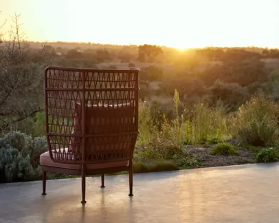 CURIO Highback Armchair positioned on a stylish outdoor deck with lush greenery.