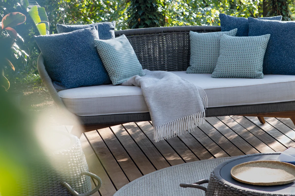 Outdoor throw draped over a sofa, providing comfort for cooler summer evenings.
