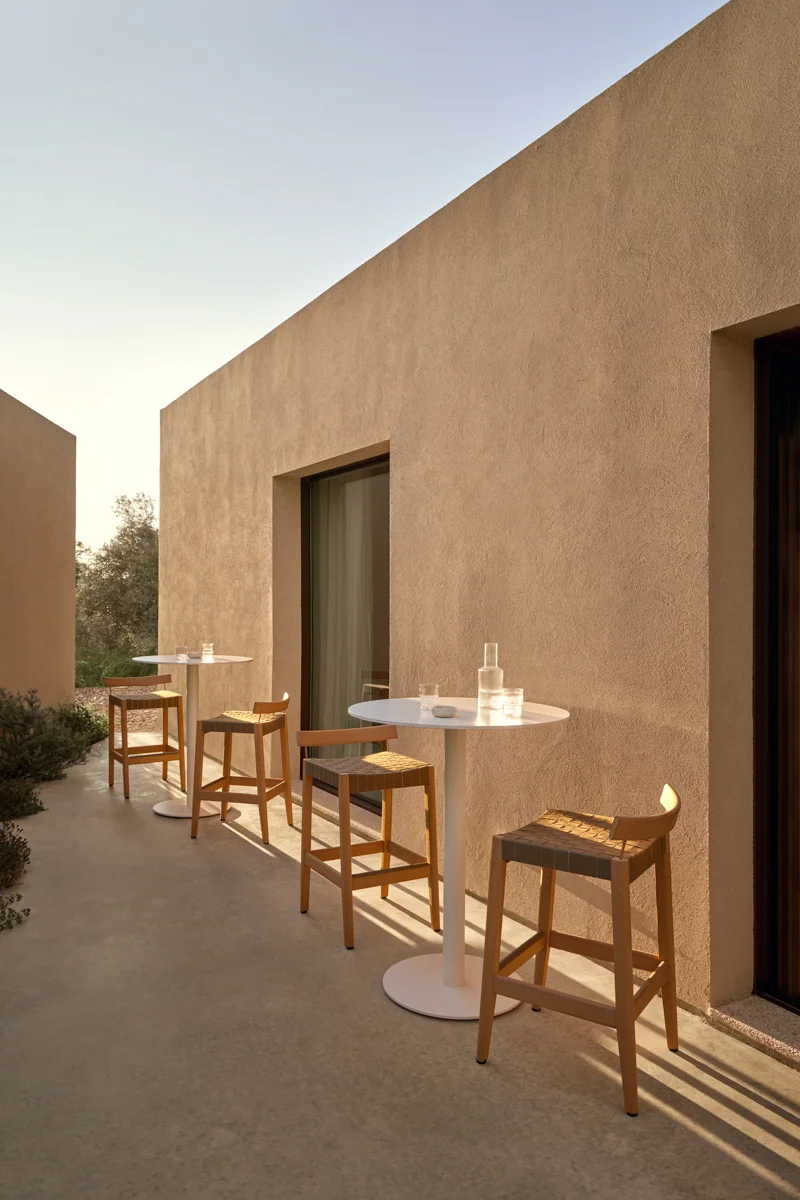 Kubik outdoor bar stools with round tables in a warm architectural entertaining area.
