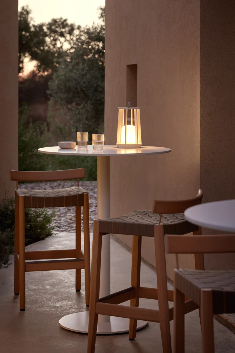 Kubik outdoor bar stools arranged around round tables with lantern lighting and refined styling.