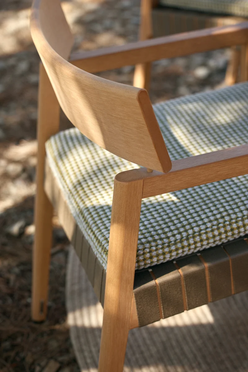 Close-up of Kubik dining chair with curved TechTeak backrest and patterned outdoor cushion.