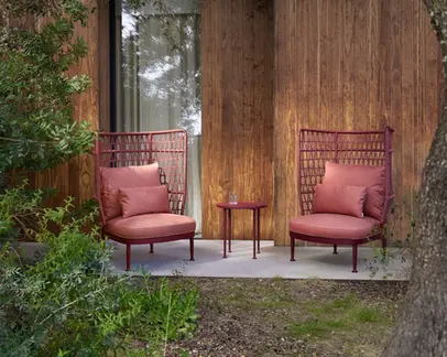 CURIO Highback Armchairs positioned on a stylish outdoor deck with lush greenery.