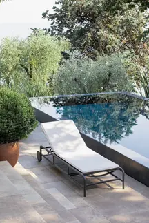 AIR Sun Lounger positioned beside a pool with scenic garden and water views