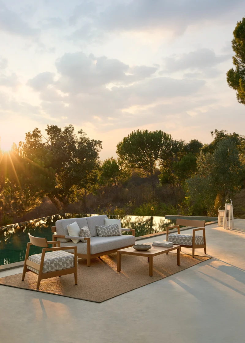 Kubik outdoor lounge furniture arranged beside a pool, with sofa, armchair and coffee table in evening light.