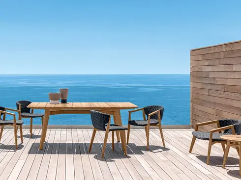 KNIT high-back outdoor lounge armchair in teak and woven rope in an outdoor setting