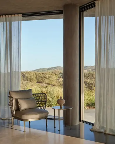 CURIO Armchair positioned on a stylish living room with lush greenery in background.