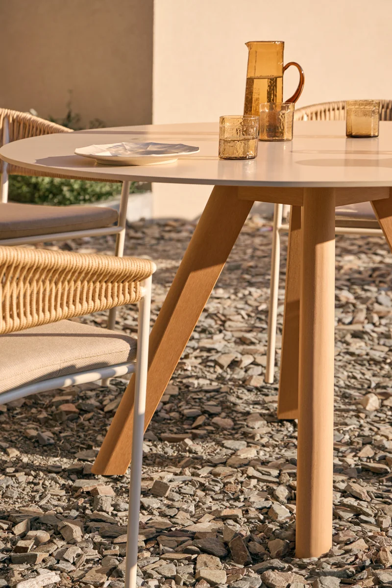 Close-up of Kubik outdoor dining table with porcelain top and warm TechTeak legs in evening light.